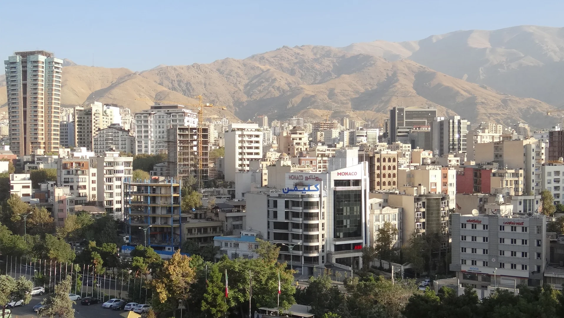 Eine Wissenschaftlerin und ein Wissenschaftler arbeiten hinter einer Glasfassade und mischen Chemikalien mit Großgeräten.